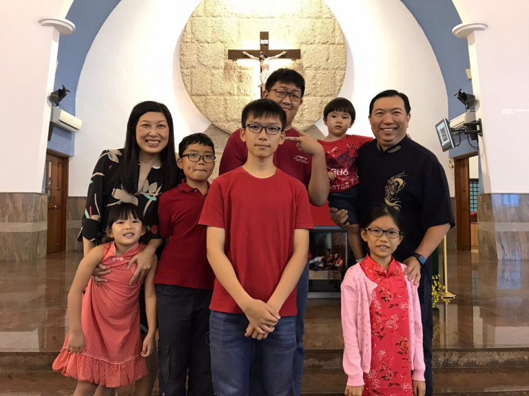 Mr Kelvin Tan's family of 8 posing in front of a church altar