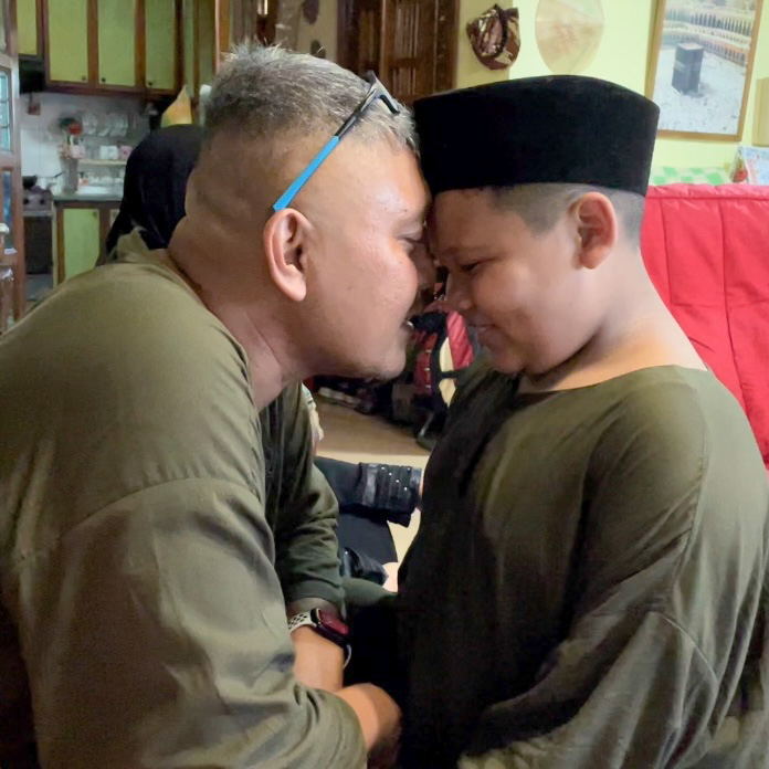 A child seeking forgiveness from his father during the family's Hari Raya celebration.