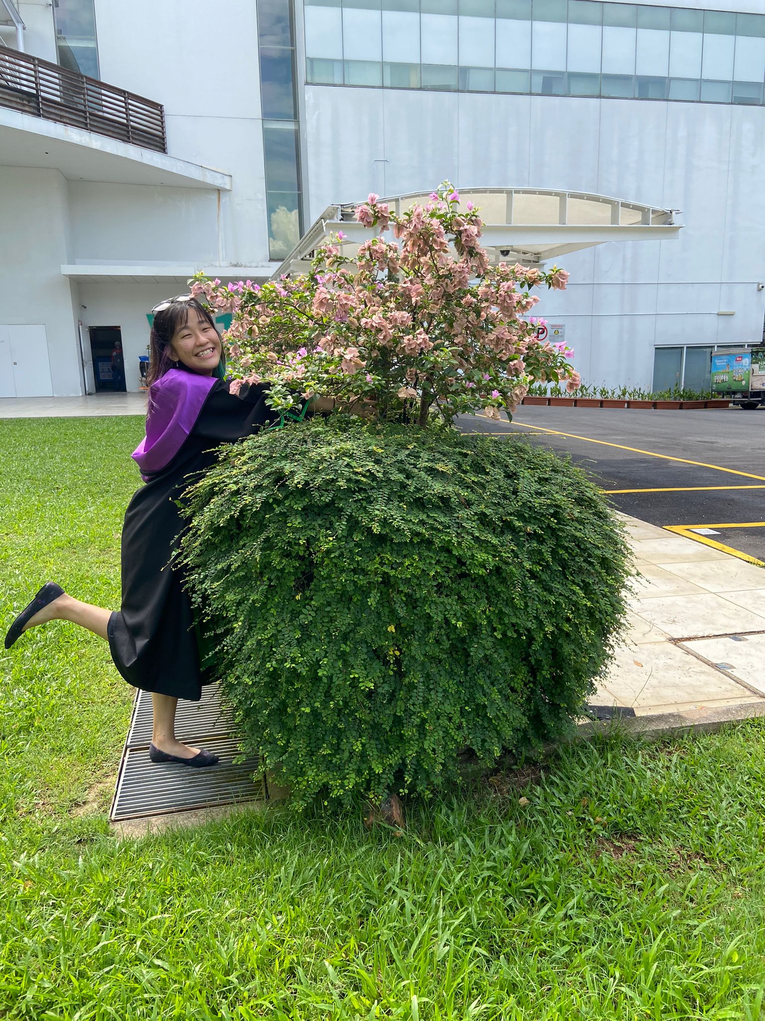 Brenda posing with a bush of flowers on her graduation day at Republic Polytechnic