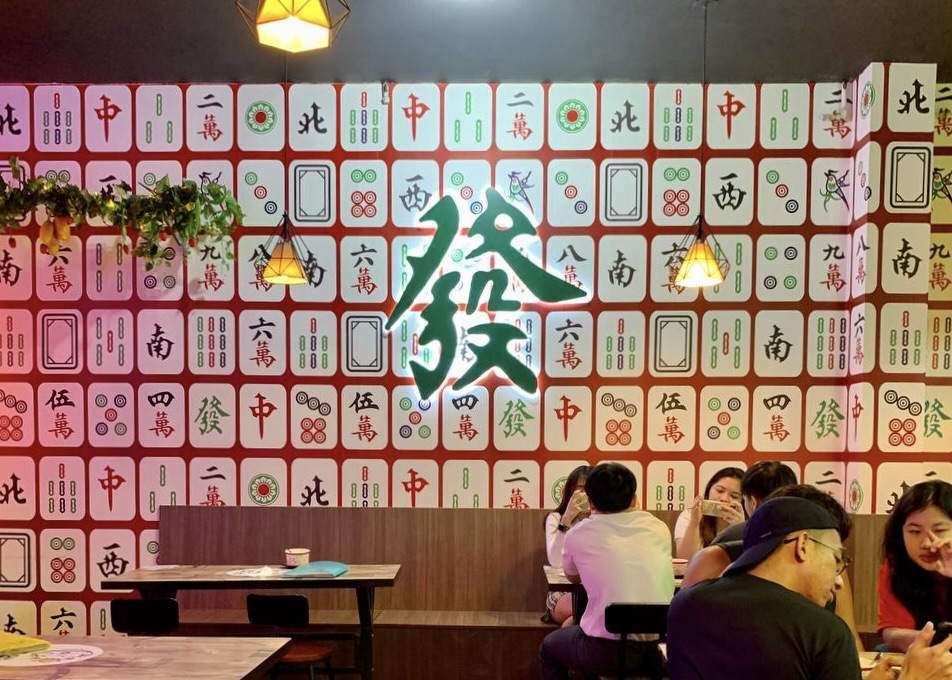 Shop interior decorated with mahjong tiles and a neon 'Huat' sign