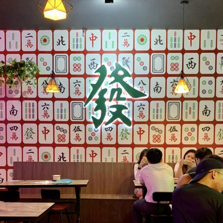 Shop interior decorated with mahjong tiles and a neon 'Huat' sign