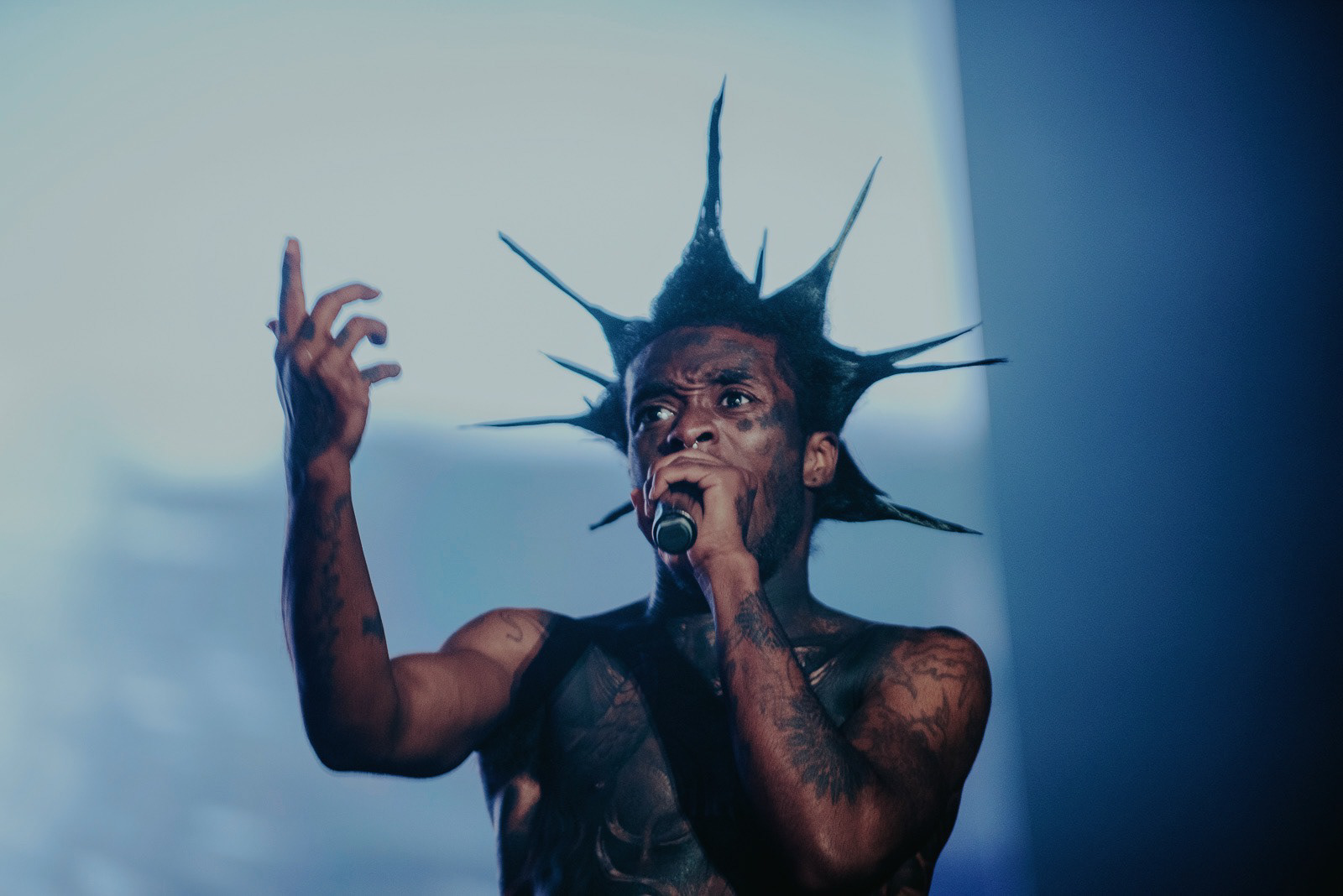 This photo shows Lil Uzi Vert with a wild spiky hairstyle passionately performing at his concert.