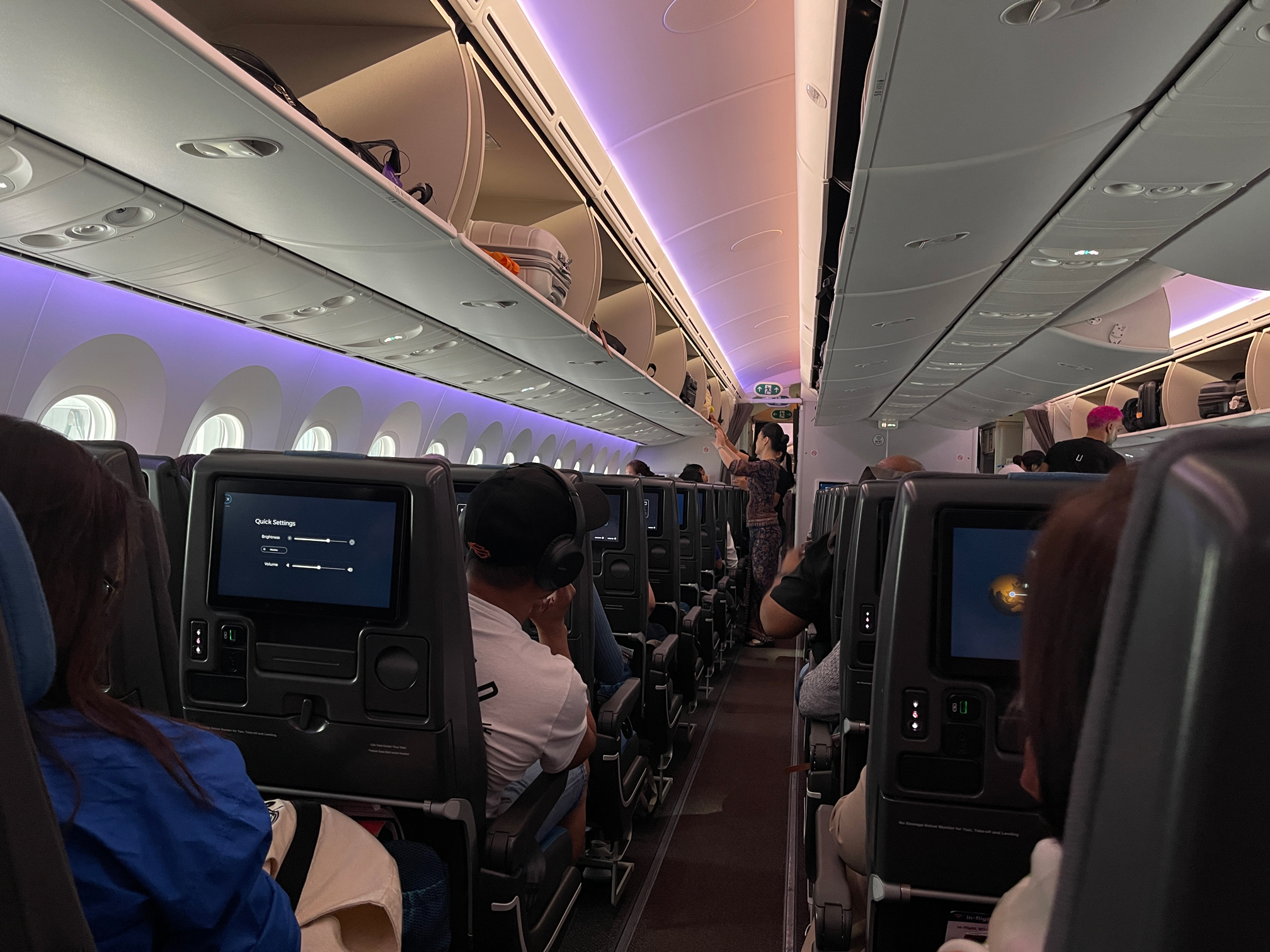 This photo shows the interior of a full airplane with dim lighting.