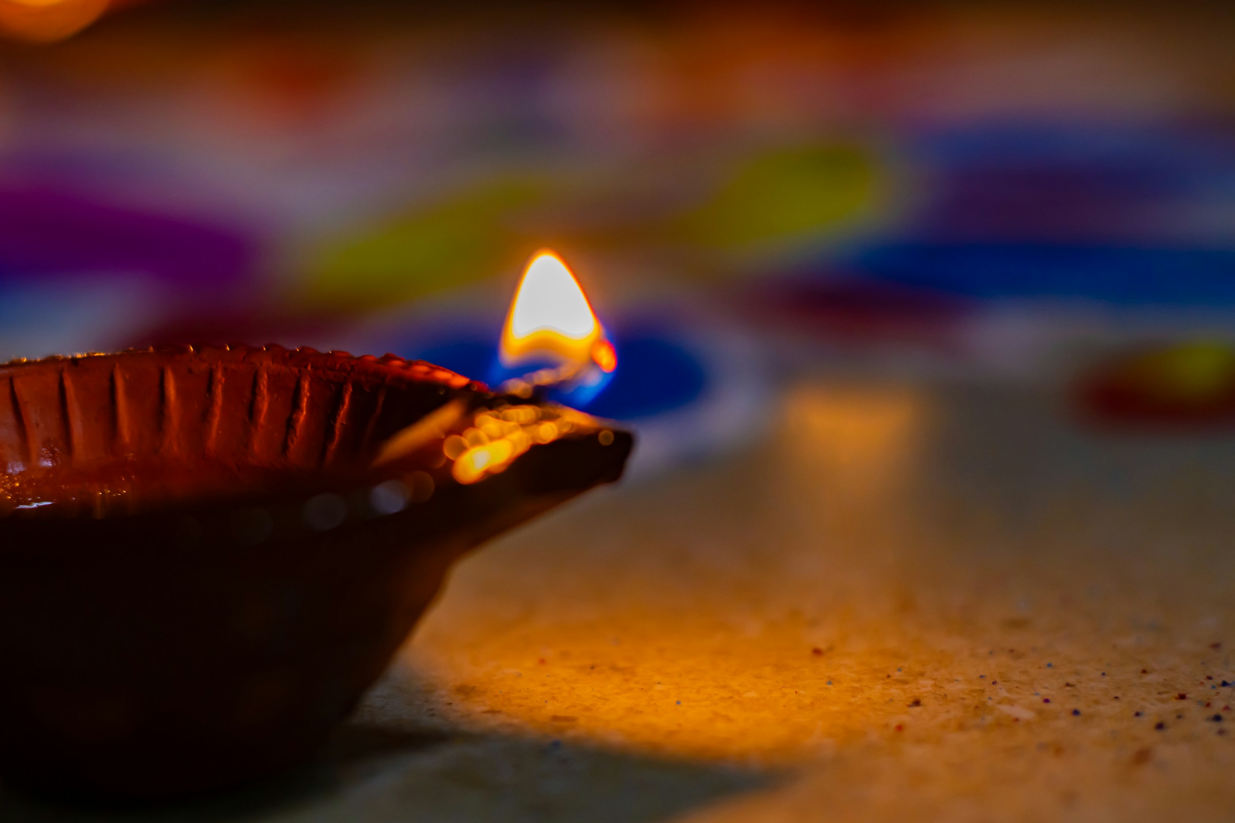 Diya lit with rangoli in the background